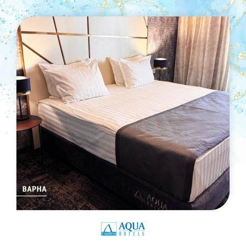 a bedroom with a large bed with white sheets and pillows at Aqua Hotel in Varna City