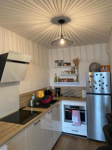 - une cuisine avec des placards blancs et un réfrigérateur en argent dans l'établissement Appartement à 15 min à pied du vieux port, à La Rochelle