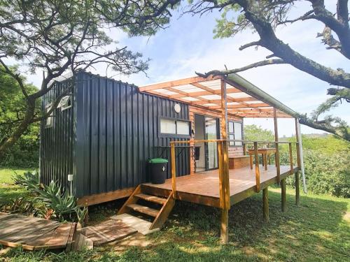 a tiny house with a deck in the grass at Freedom Tiny Homes Resort in East London