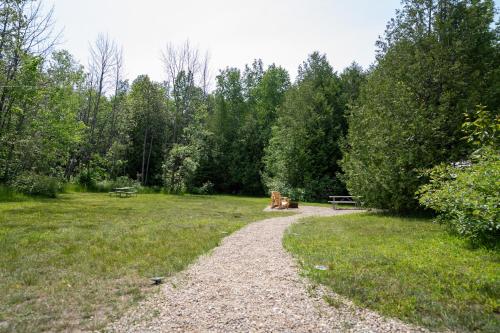 a path in a park with a bench and trees at Grotto Getaway in Miller Lake