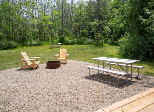 two benches and a picnic table in a park at Grotto Getaway in Miller Lake
