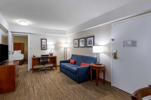 a hotel room with a blue couch and a desk at Comfort Inn University Durham - Chapel Hill in Durham