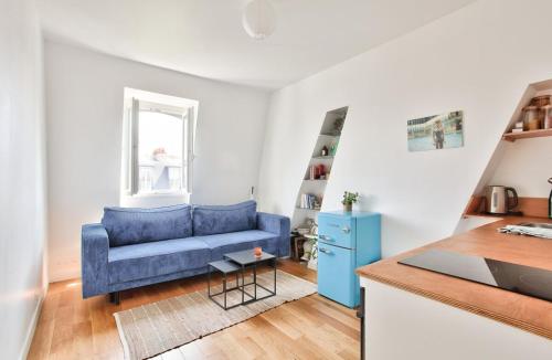 un salon avec un canapé bleu et une table dans l'établissement Appart central vue tour-Eiffel, à Paris