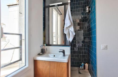 une salle de bain avec un lavabo et un miroir dans l'établissement Appart central vue tour-Eiffel, à Paris