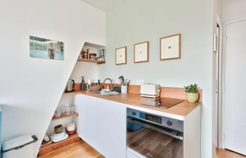 une cuisine blanche avec un évier et un comptoir dans l'établissement Appart central vue tour-Eiffel, à Paris
