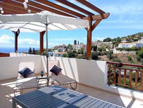 a patio with a table and chairs and an umbrella at Sunset Apartment in Peyia