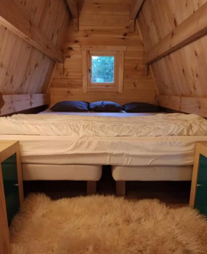 Ce lit se trouve dans une cabane en rondins dotée d'une fenêtre. dans l'établissement Tipi en bois tout équipé avec balnéo, à Rillieux-la-Pape