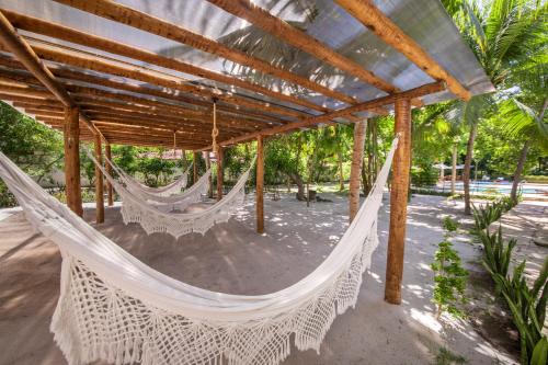a hammock in a pavilion with palm trees at Pousada Ponta de Mangue in Maragogi