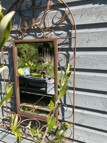 a mirror sitting on the side of a house at The Bell Ringers Cottage in Loddiswell