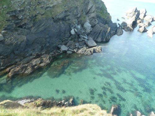 a large body of water next to a rocky shore at The Bell Ringers Cottage in Loddiswell