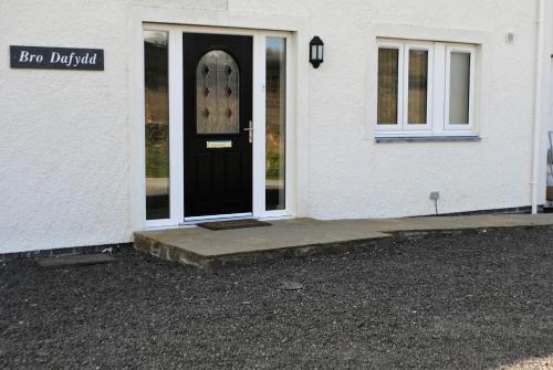 a white house with a black door with a sign on it at Bro Dafydd in Aberystwyth