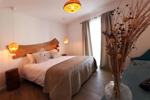 a bedroom with a bed and a vase with flowers at Cangalho Village House Premium in Azueira