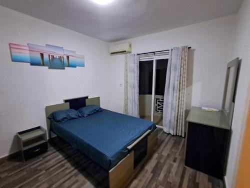 a bedroom with a blue bed and a window at Residence les orchidees D5 in Flic-en-Flac
