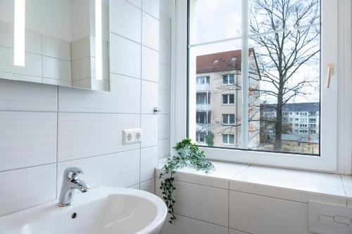 a white bathroom with a sink and a window at Atelierwohnung am Stadtpark in Chemnitz