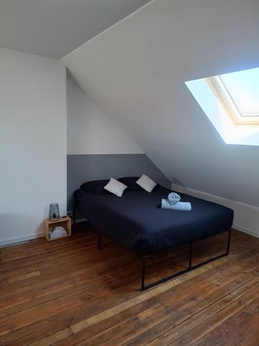 une chambre avec un lit avec des draps bleus et une fenêtre dans l'établissement Le GM - appartement proche gare et commerces, à Saint-Quentin