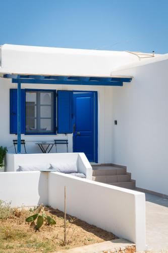 a white house with a blue door and stairs at Aitheras Luxury Suites in Protorgia