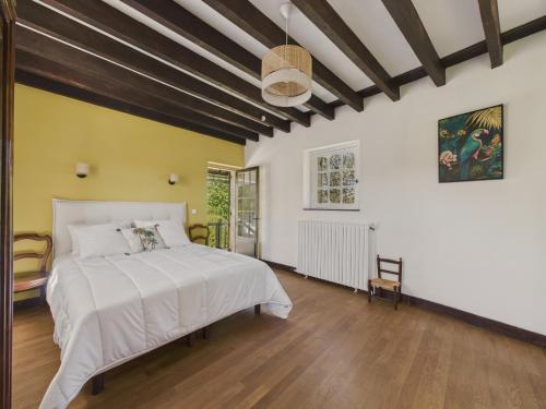 una camera da letto con un grande letto bianco e pavimenti in legno di Jolie maison avec jacuzzi pour 8 personnes a Mauzens-et-Miremont