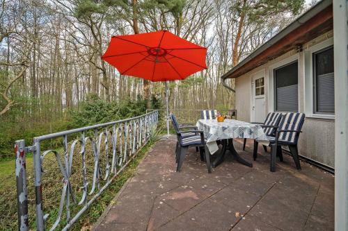 a table and chairs with a red umbrella on a porch at Baumfuchs Ferienbungalow in Wesenberg