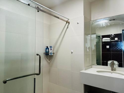 a white bathroom with a shower and a sink at 1 Bedroom Unit In Bamboo Bay in Mandaue City