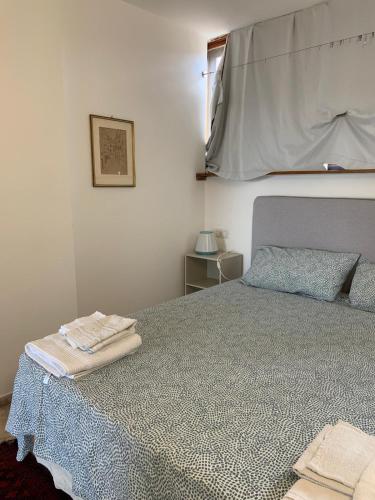 a bedroom with a bed with a blanket and a window at LightHouse in Albissola Marina