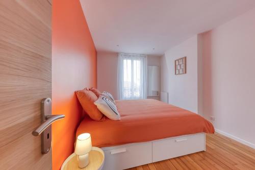 Schlafzimmer mit einem Bett mit einem orangefarbenen Kopfteil in der Unterkunft L'Eden - Porte de Paris - 10 min Stade de France in Saint-Denis