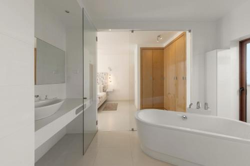 a white bathroom with a tub and a sink at Charming Villa Óbidos by LovelyStay in Casal do Narcizo