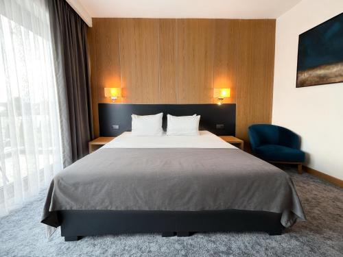 a hotel room with a bed and a blue chair at GAZDA Hotel&Restaurant - Self Chek-In in Jesenice