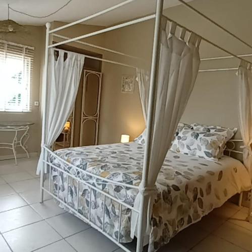 une chambre avec un lit à baldaquin dans l'établissement Aux 40 Écus - Gingko, à Puycornet