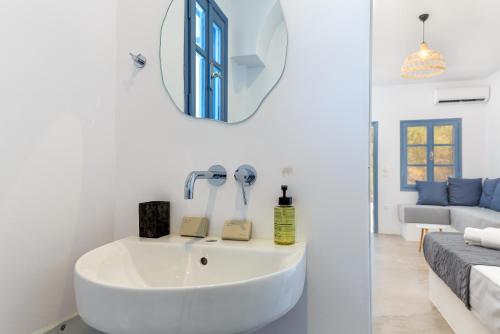 a white bathroom with a sink and a mirror at Aitheras Luxury Suites in Protorgia
