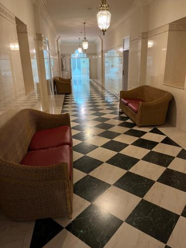 a lobby with two chairs and a checkered floor at Hotel Parque Balneario Termas Pallares in Alhama de Aragón