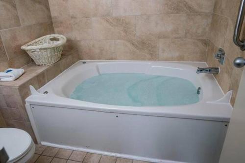 une baignoire remplie d'eau bleue dans une salle de bain dans l'établissement Four Sails Resort, à Virginia Beach