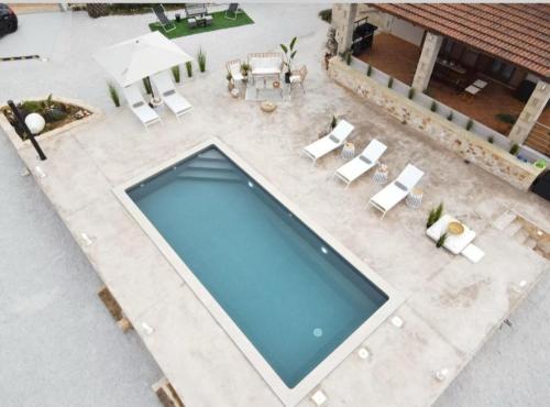 an overhead view of a pool with chairs and an umbrella at Stone villa Halepa panoramic view, private pool,big garden & quiet in Néon Khoríon