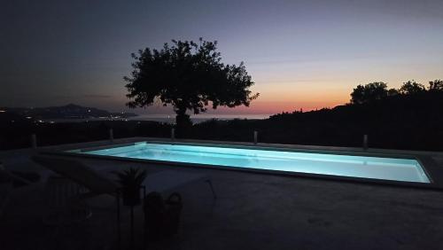 a swimming pool at night with a tree in the background at Stone villa Halepa panoramic view, private pool,big garden & quiet in Néon Khoríon