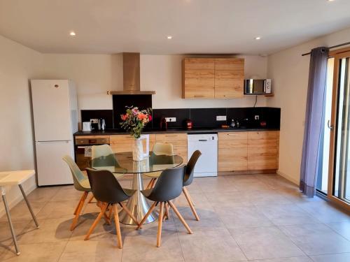 une cuisine avec une table en verre, des chaises et un comptoir dans l'établissement Le Jura entre Annecy et Genève, à Feigères