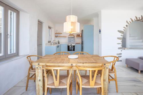 a kitchen and dining room with a wooden table and chairs at Olea Tinos, A Luxury Villa in Kardiani