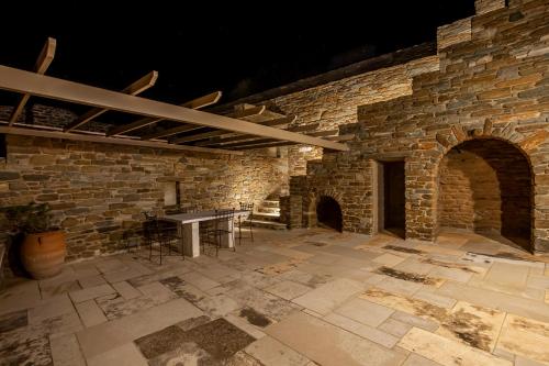a stone room with a table and a stone wall at Olea Tinos, A Luxury Villa in Kardiani