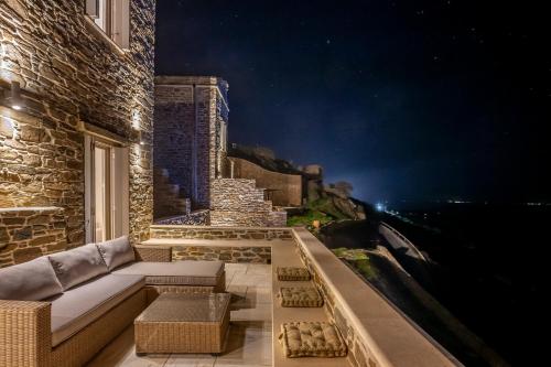 a room with a couch on a balcony at night at Olea Tinos, A Luxury Villa in Kardiani