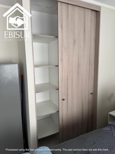 a bedroom with a book shelf next to a closet at EBISUR Apart - Hoteles OROMPELLO in Concepción