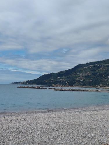 a beach with a rocky shoreline with a mountain at Casa Fronte Mare in Ospedaletti