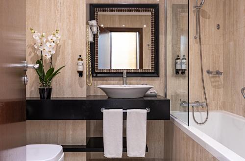 a bathroom with a sink and a mirror and a tub at Pestana Alvor Praia Premium Beach & Golf Resort in Alvor