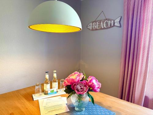 a table with a vase of flowers and bottles ofbeer at Haus Friesenfeuer in Nieblum