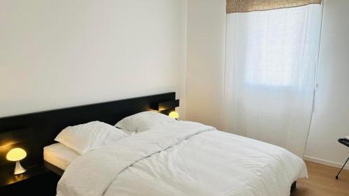 une chambre avec un lit avec des draps blancs et des oreillers dans l'établissement Appartement ELISA Calvi, à Calvi