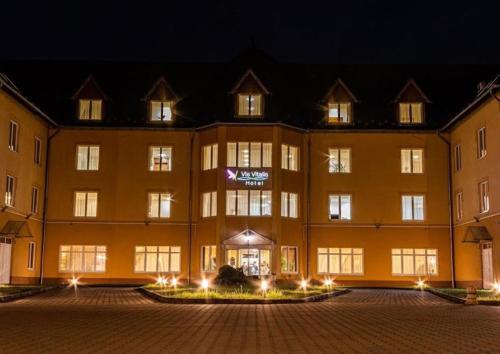 a large yellow building with lights in front of it at Vis Vitalis Hotel in Kerepes