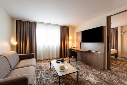 a hotel room with a couch and a flat screen tv at Novotel Paris Gare De Lyon in Paris