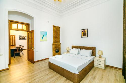 a white bedroom with a bed and a table at Apartment AERİA in Baku