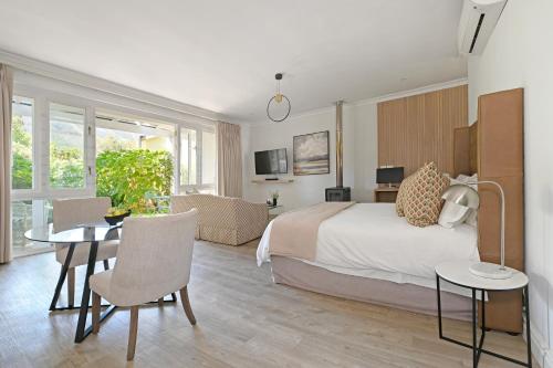 a bedroom with a bed and a table and chairs at Fransvliet Guest House in Franschhoek