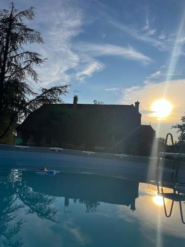 une piscine d'eau avec un coucher de soleil derrière un bâtiment dans l'établissement Villa Bernoux, à Sagy