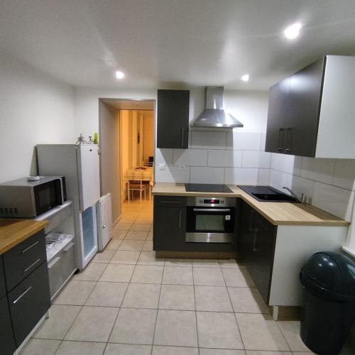 une cuisine avec des armoires noires et un four à plaques de cuisson dans l'établissement Appartement avec cour fermée, à Andelot