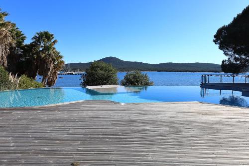 une grande piscine à côté d'un corps d'eau dans l'établissement T2 élégant avec piscine chauffée & plage privée, à Pianottoli-Caldarello