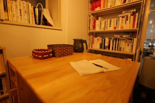 a wooden table with a napkin and a pen on it at yol Guesthouse ヨルゲストハウス in Takeo